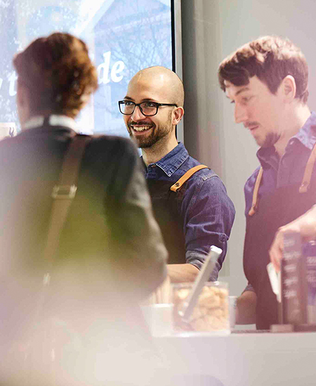 Lächelnder goldenblack Barista bei der Arbeit